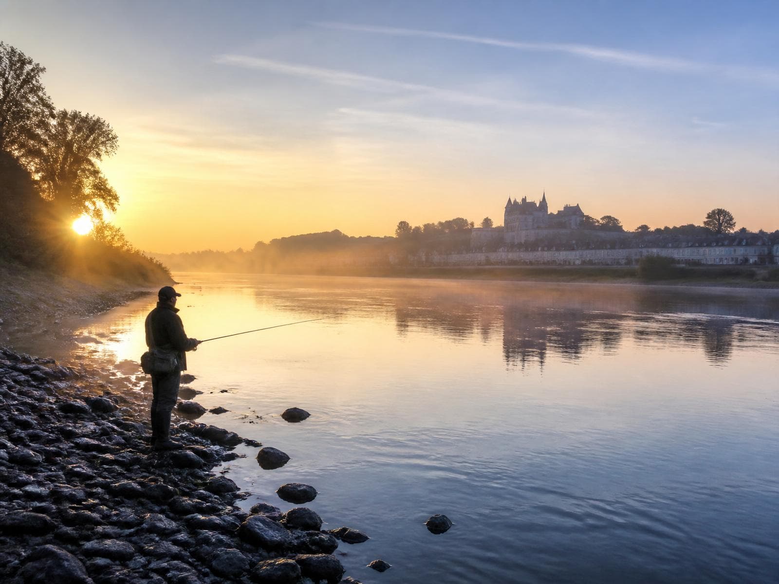 Angler fishing the Loire at dawn with a château on the horizon